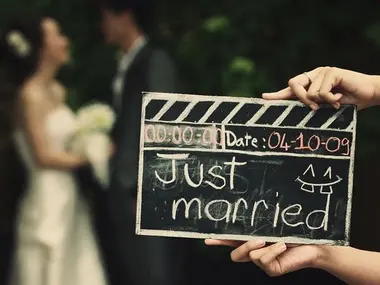 Para młoda w tle, na pierwszym planie klaps filmowy z napisem Just married