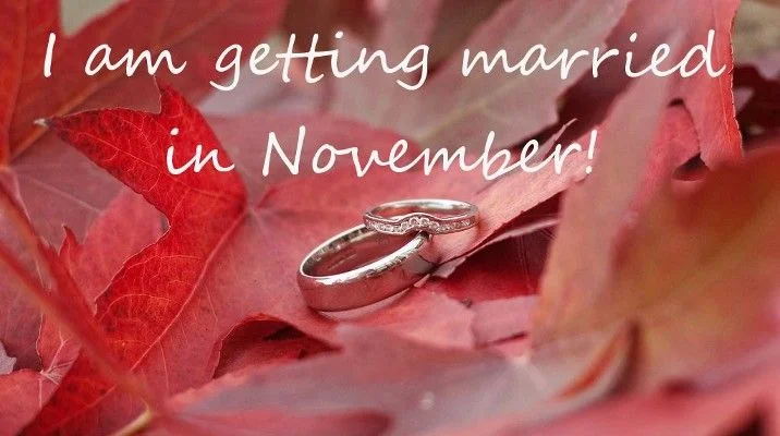 Dwie obrączki na czerwonych jesiennych liściach z napisem I am getting married in November