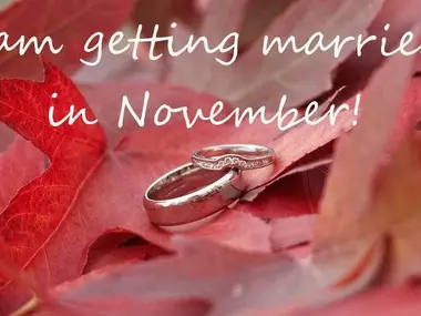 Dwie obrączki na czerwonych jesiennych liściach z napisem I am getting married in November