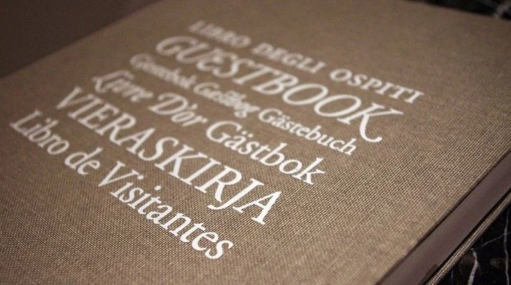 Otwarta księga gości z odręcznymi wpisami i długopisem