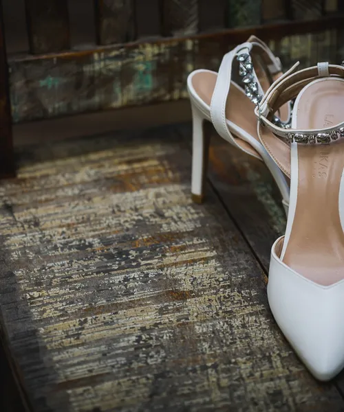 Białe ślubne buty z kamieniami na drewnianym krześle