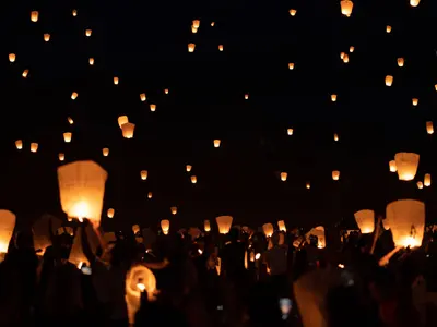 Goście wypuszczają setki płonących lampionów szczęścia na tle nocnego nieba