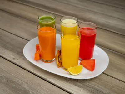 Szklanki z kolorowymi sokami owocowymi i warzywnymi na białym talerzu na drewnianym stole