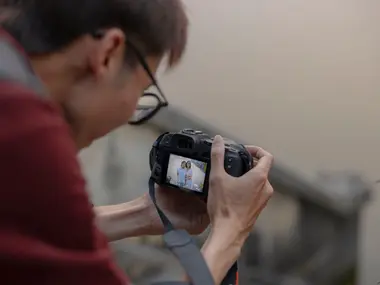 Fotograf ogląda na ekranie aparatu zdjęcie pary zrobione podczas sesji