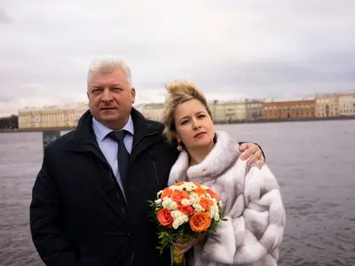 Dojrzała para młoda nad rzeką, kobieta w futrze trzyma pomarańczowy bukiet róż