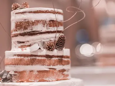 Dwupiętrowy tort typu naked cake ozdobiony szyszkami i suszonymi liśćmi