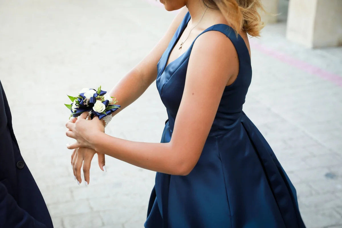 Druhna w granatowej sukience z kwiatowym korsażem z białych i granatowych kwiatów na nadgarstku