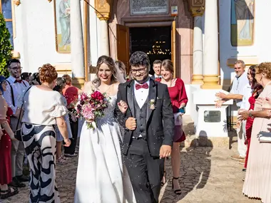 Para młoda wychodzi z kościoła, goście obsypują ją i witają przed wejściem