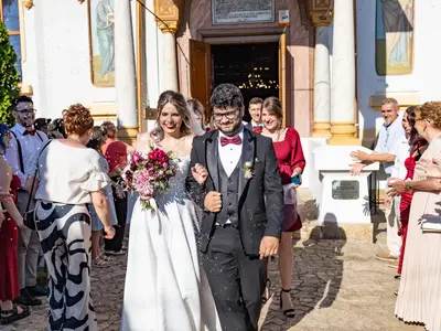 Para młoda wychodzi z kościoła, goście obsypują ją i witają przed wejściem