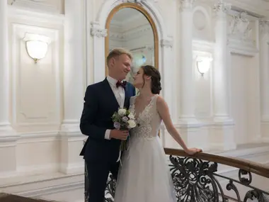 Para młoda przy kutej balustradzie w jasnej, eleganckiej sali urzędu ze sztukaterią