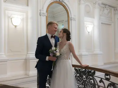 Para młoda przy kutej balustradzie w jasnej, eleganckiej sali urzędu ze sztukaterią