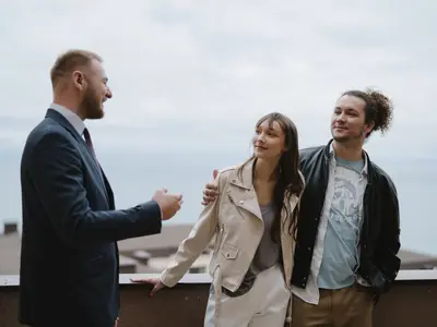 Młoda para rozmawia z doradcą nieruchomości na tarasie oglądanego mieszkania