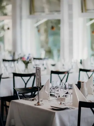 Jasna sala restauracji z nakrytymi białymi obrusami stołami przygotowanymi na przyjęcie