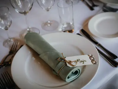 Winietka z imieniem przywiązana sznurkiem do zielonej serwetki na białym talerzu