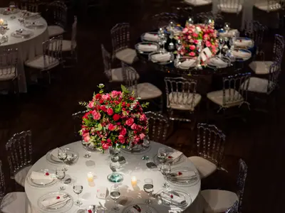Okrągłe stoły weselne nakryte dla gości z bukietami czerwonych róż, widok z góry