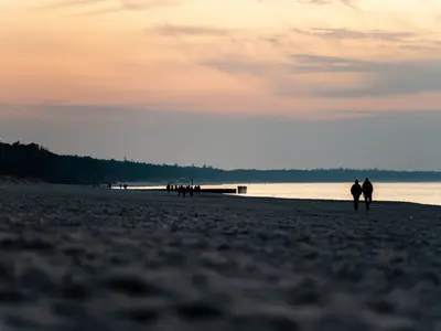 Para spaceruje o zachodzie słońca po plaży nad Bałtykiem w Kołobrzegu