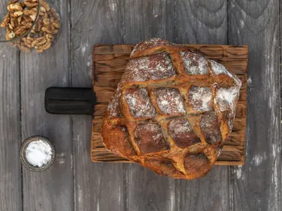 Bochen wiejskiego chleba na drewnianej desce obok miseczki z solą