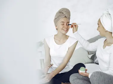 Przyjaciółki w turbanach z ręczników robią sobie makijaż podczas domowego spa