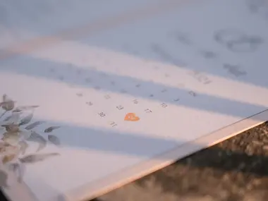 Kartka save the date z kalendarzem i datą ślubu zaznaczoną pomarańczowym serduszkiem