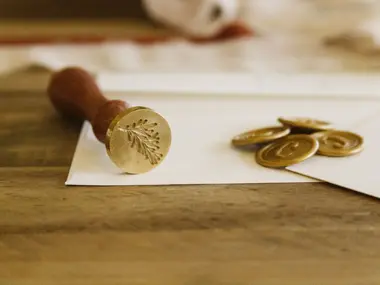 Mosiężna pieczęć do laku i złote pieczęcie woskowe na kopercie zaproszenia ślubnego
