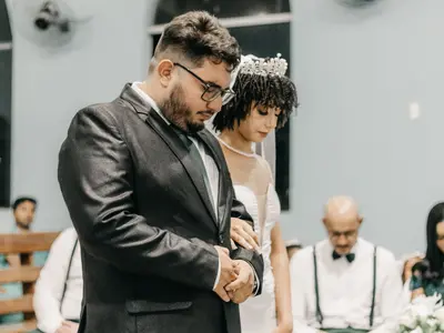 Pan młody ze spuszczoną głową i panna młoda w diademie podczas skupionej ceremonii