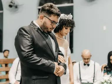 Pan młody ze spuszczoną głową i panna młoda w diademie podczas skupionej ceremonii