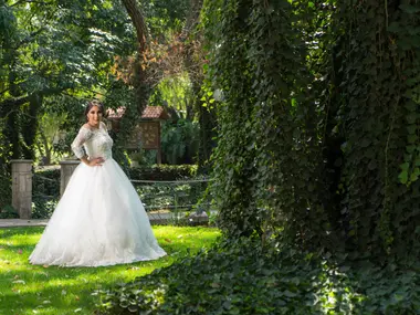 Panna młoda w sukni o kroju princessy z koronkowym gorsetem i tiulową spódnicą w ogrodzie