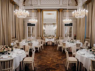 Elegancka sala bankietowa z kryształowymi żyrandolami, okrągłymi stołami i kwiatowymi stroikami