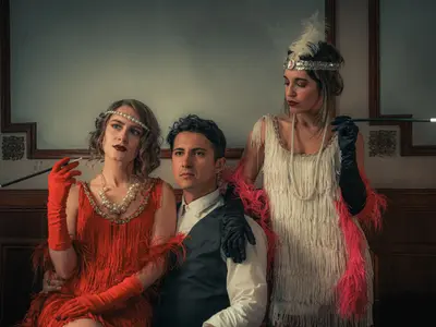 Dwie kobiety w strojach flapper z lat 20. z perłami i cygarniczkami obok mężczyzny
