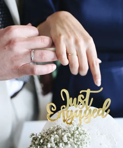 Para zakłada pierścionek zaręczynowy obok napisu „Just Engaged”