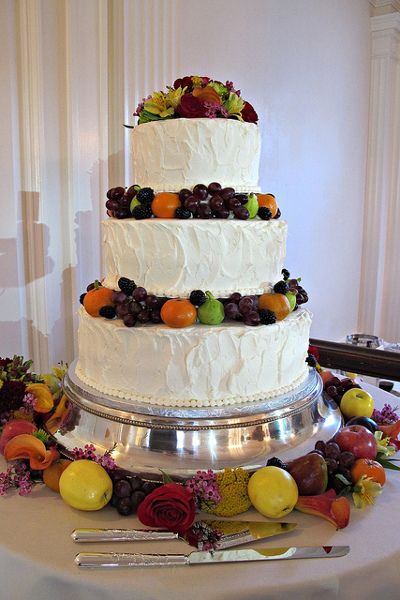 Piękny piętrowy tort ozdobiony świeżymi owocami i kwiatami